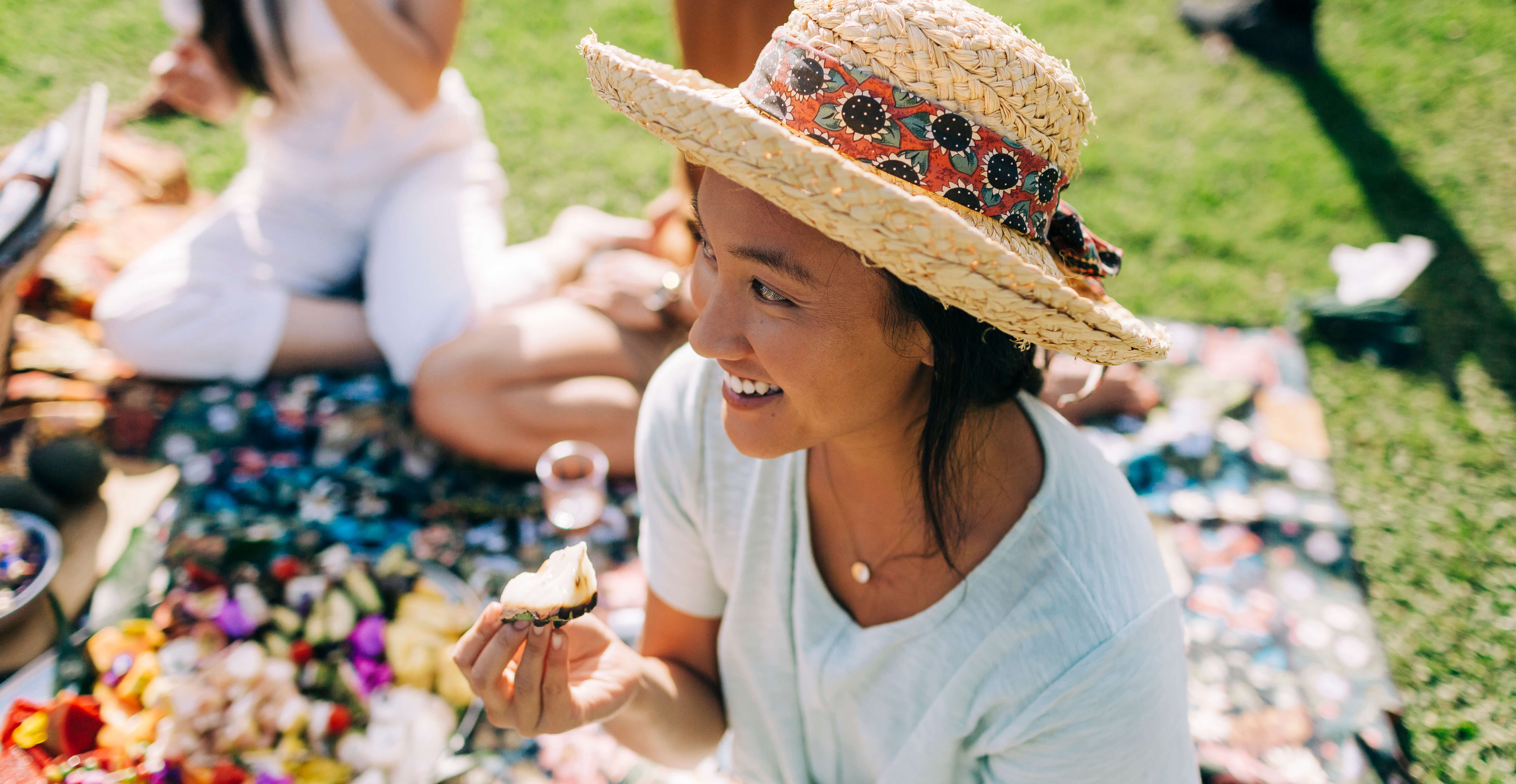 Woman with a hat enjoying some food at a picnic with friends