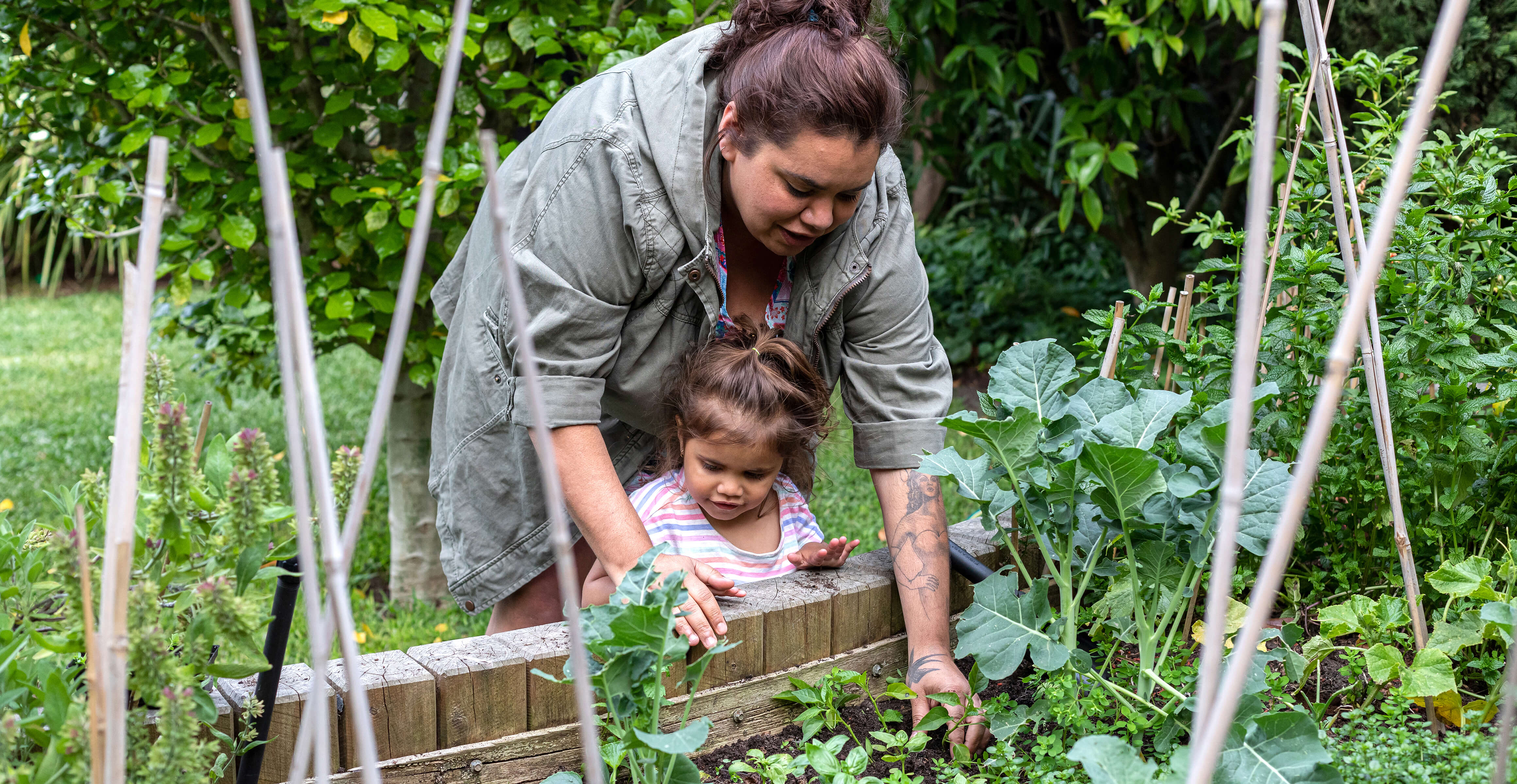 Indigenous women helping her young daughter in the garden