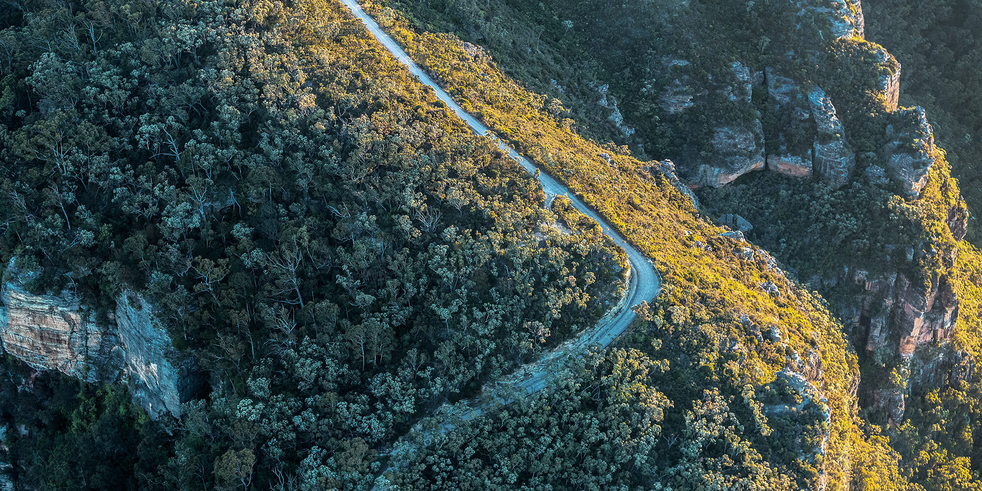Landscape of a small road winding through the bush and rocky outcrops in the Blue Mountains National park