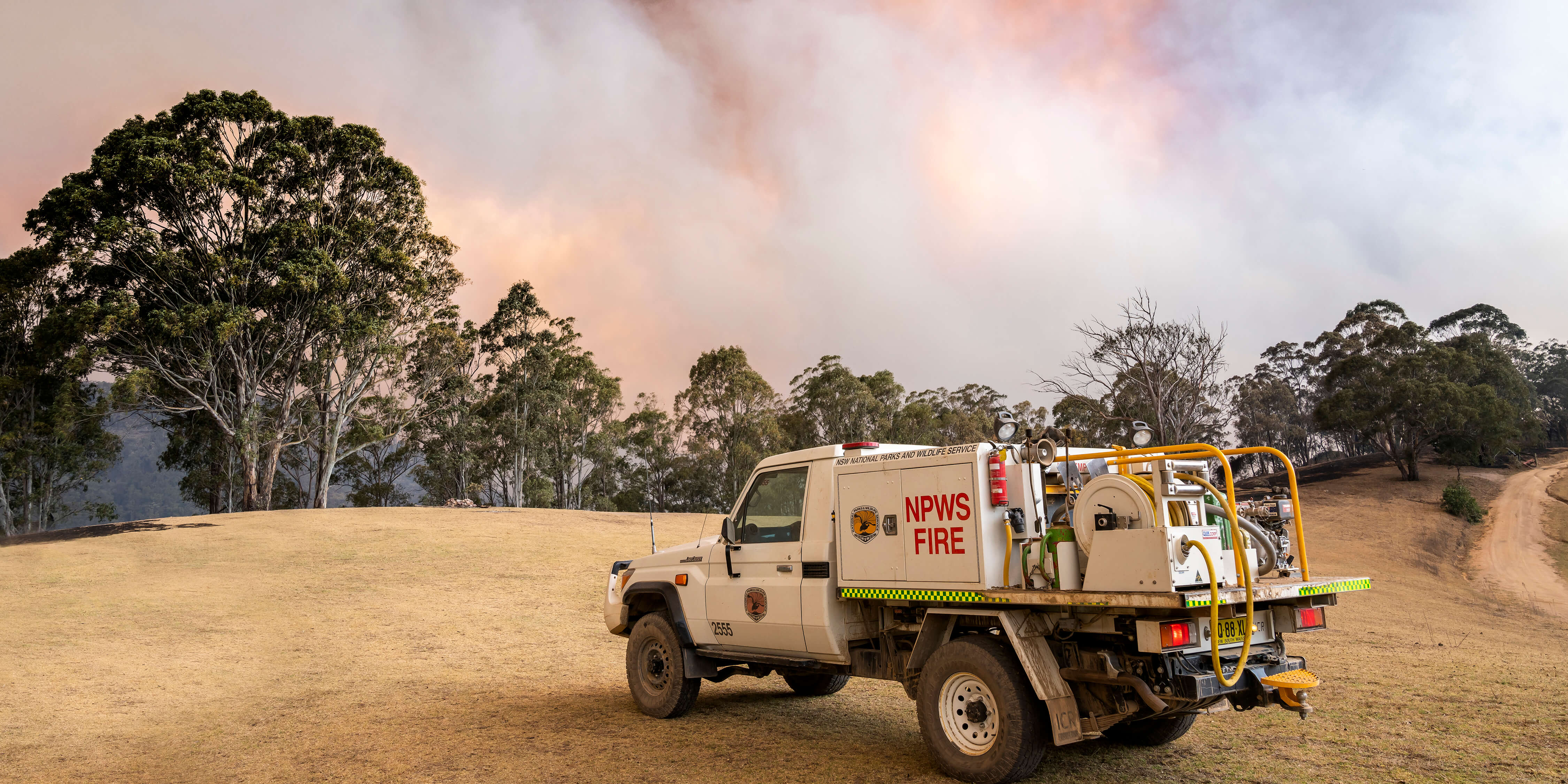 NSW National Parks and Wildlife Service fire truck with bushfires smoke in the background  