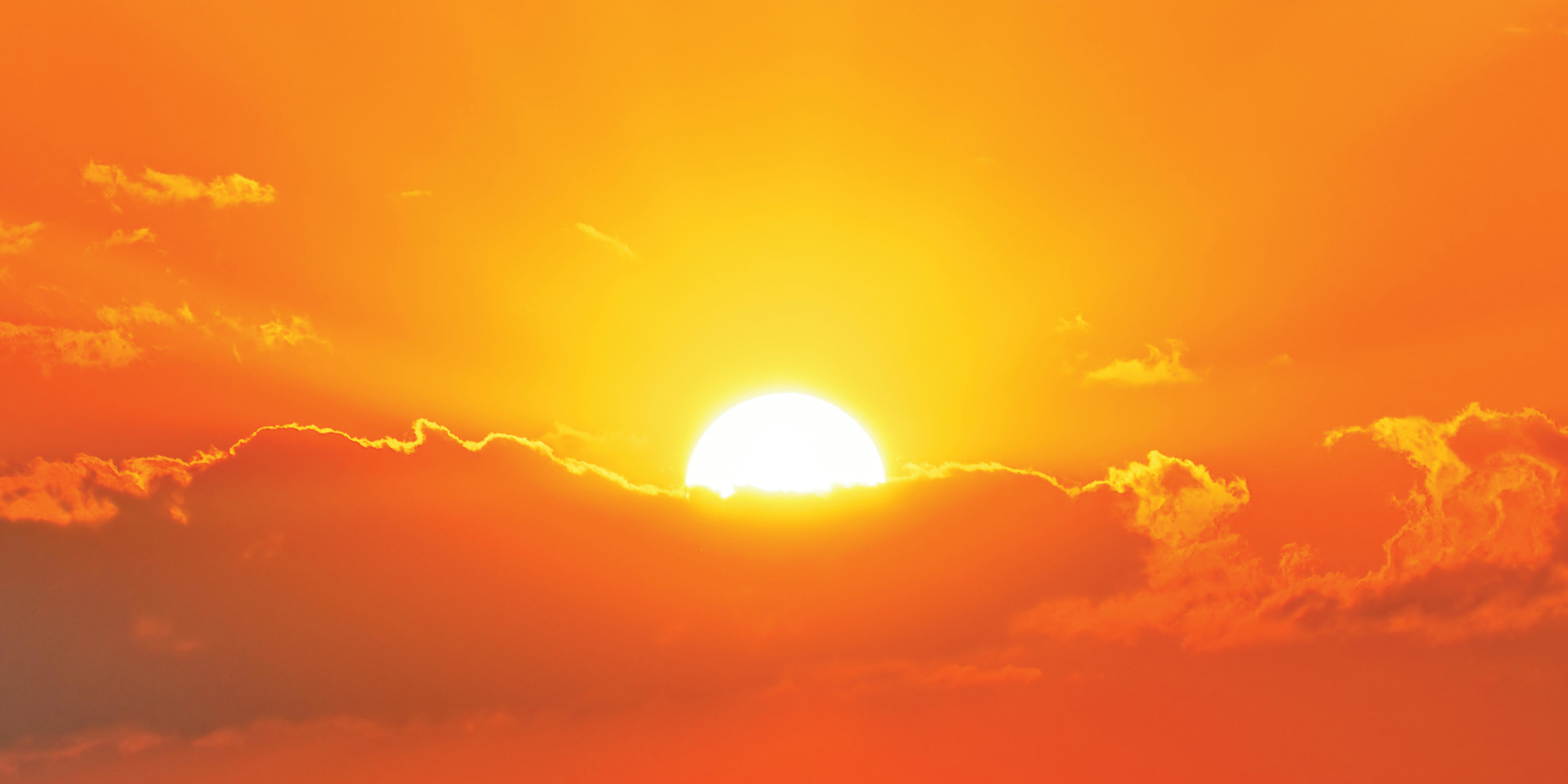 hot sun shining in an orange sky with clouds
