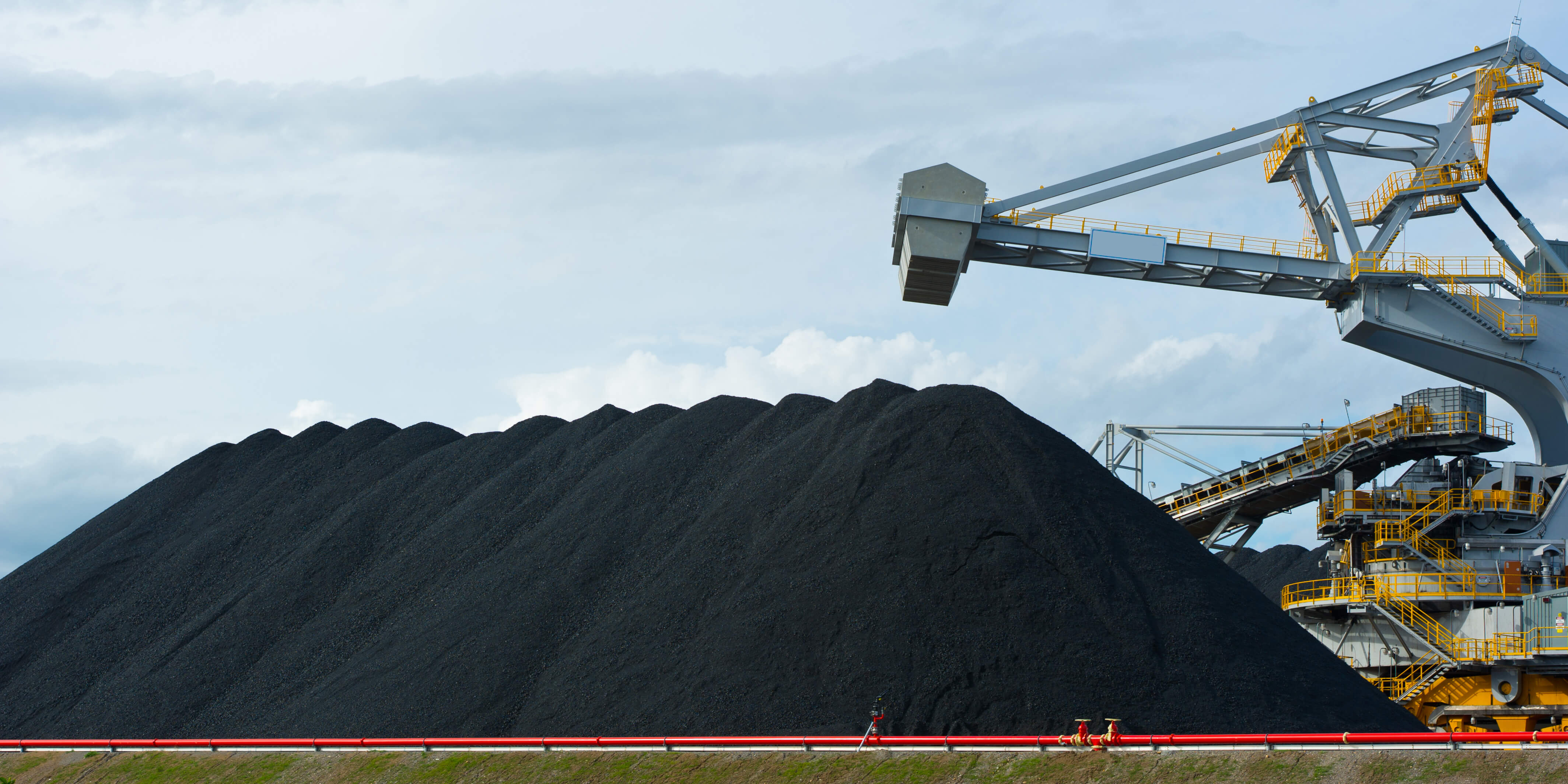 A large stack of coal with part of a reclaimer on the right hand side