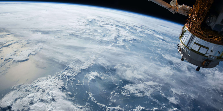 Ocean and clouds seen from space with part of a satellite.