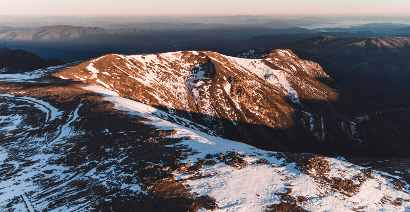 Landscape showing the sun lighting up a mountain at sunrise in the snowy mountains, NSW