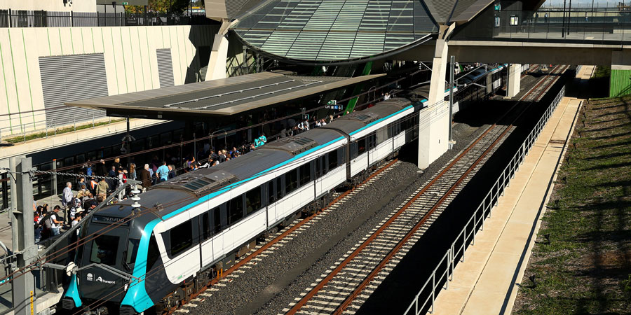 View of a newly built train station with train on the left side of the image and people on the platform