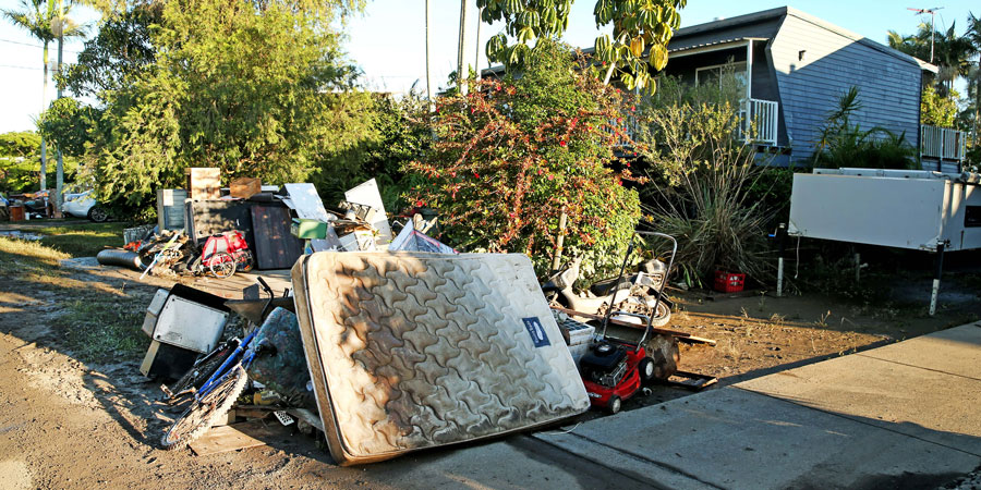 flood damaged property including a muddy mattress outside of a house after a flood