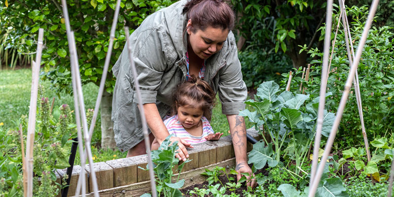 Indigenous women helping her young daughter in the garden