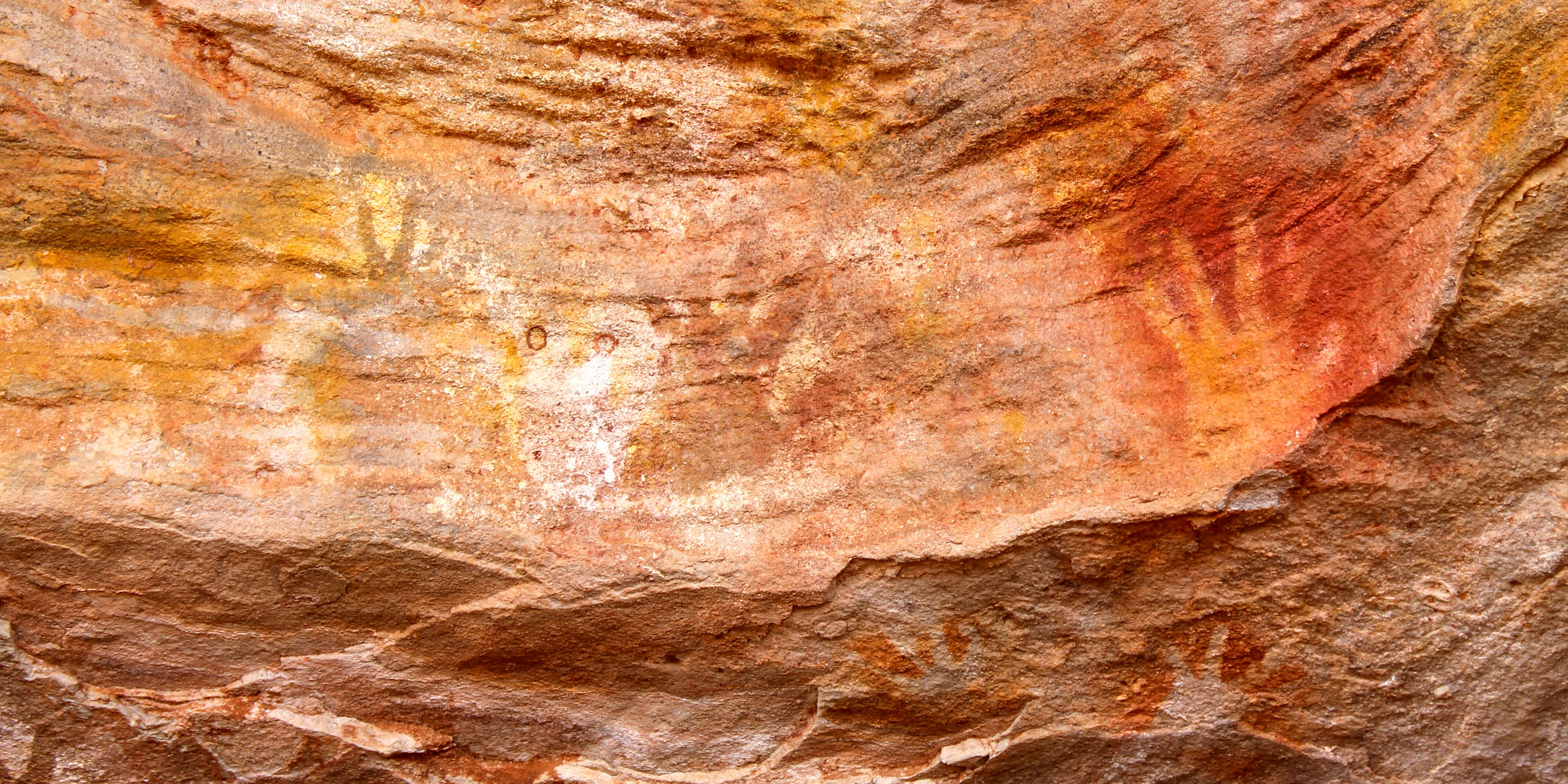 Aboriginal art showings hands on a rocky wall