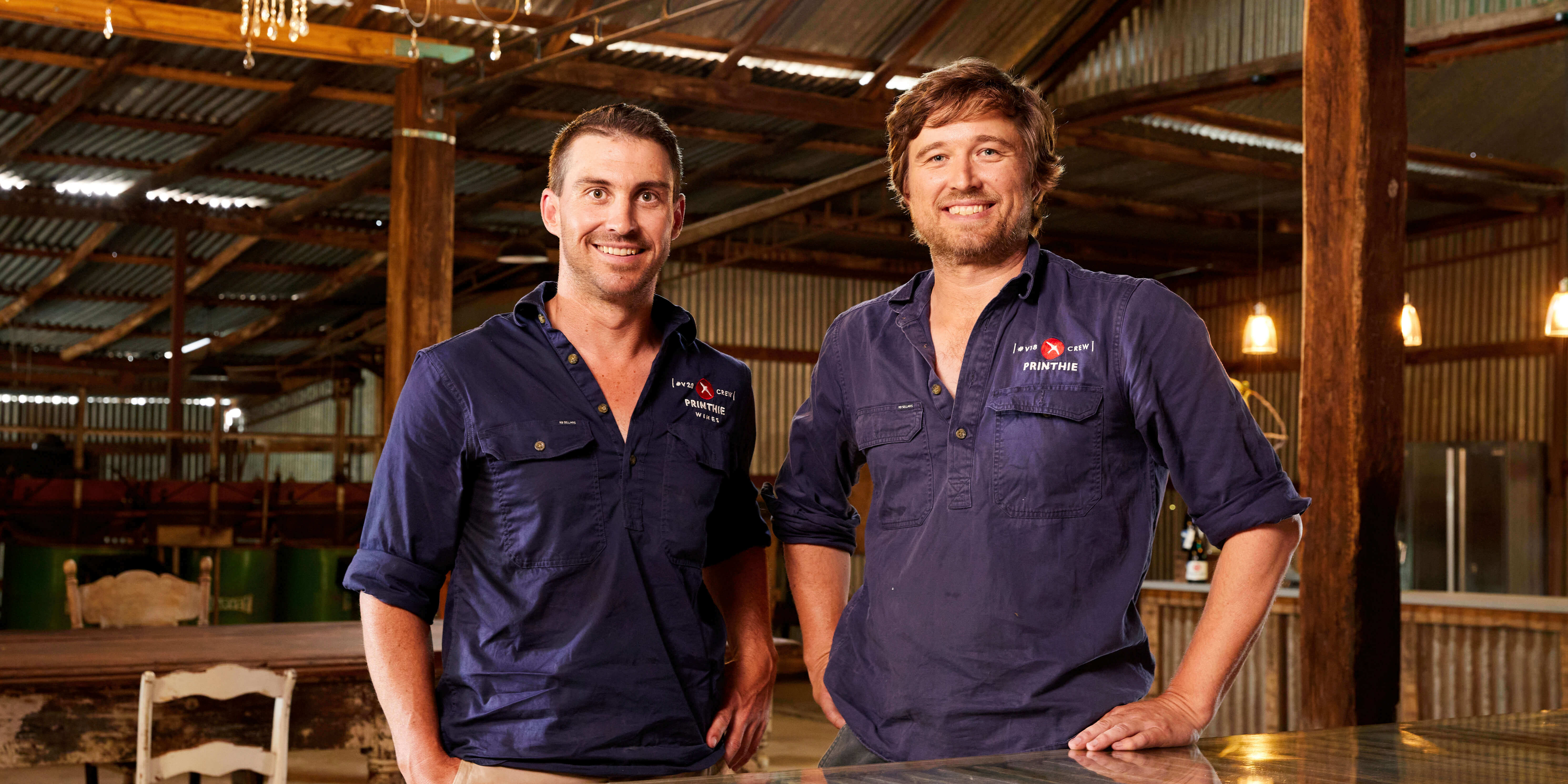 2 small business owners in their cellar smiling at the camera