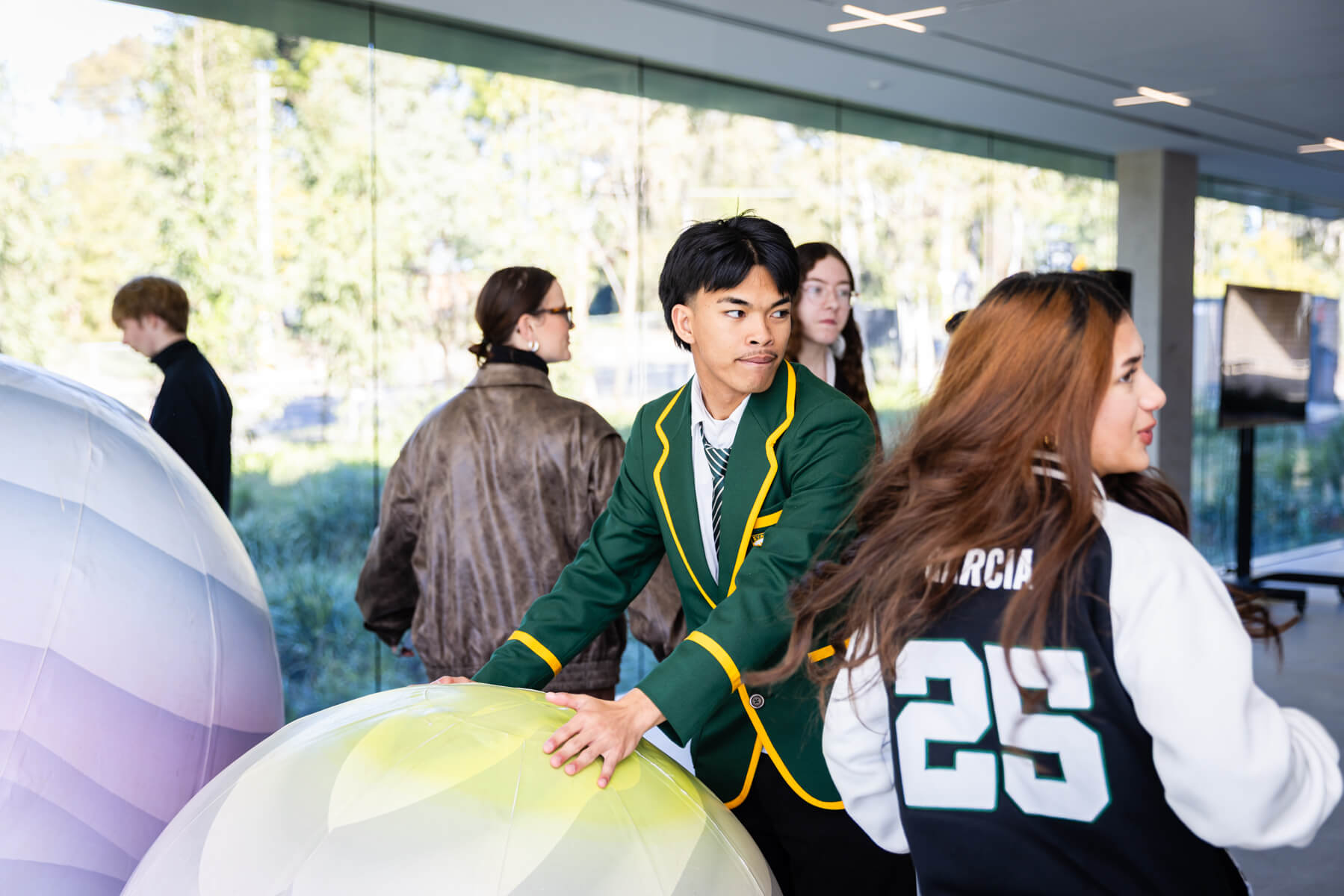 High school students gather around large, colourful inflatable balls.