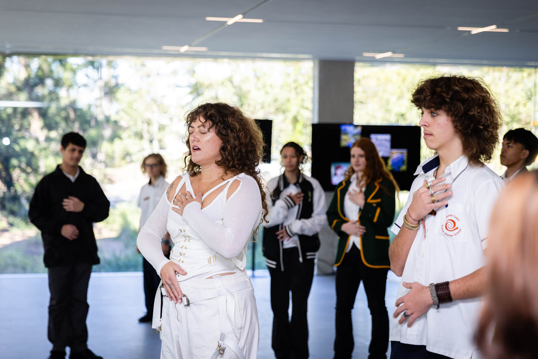 Artist Melissa Gilbert stands confidently with one hand on her heart and the other on her stomach as she leads a room of students in a breathing and grounding exercise.