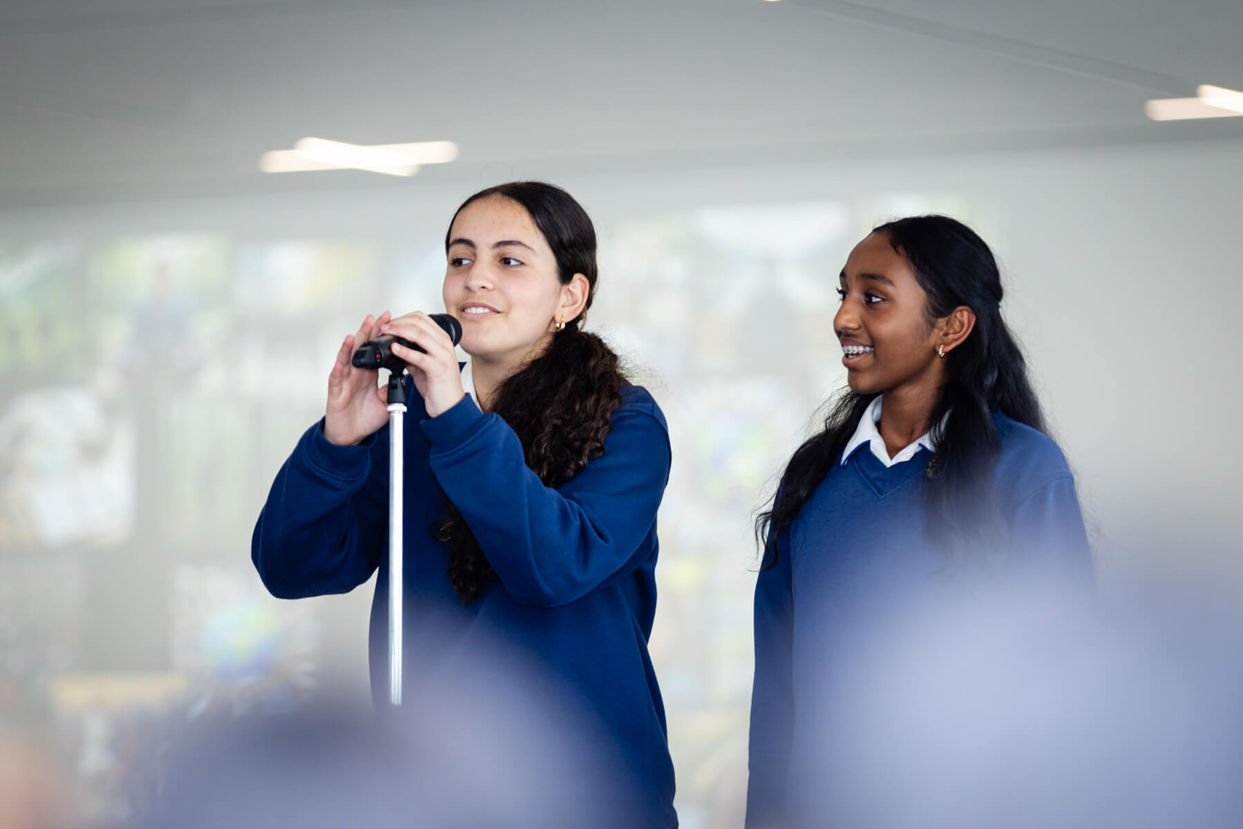 Two high school students speak at a microphone. 