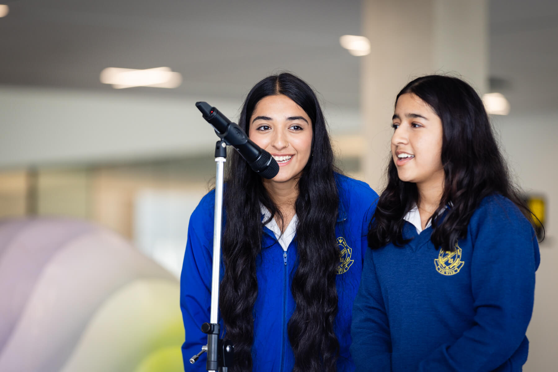 Two high school students speak at a microphone. 