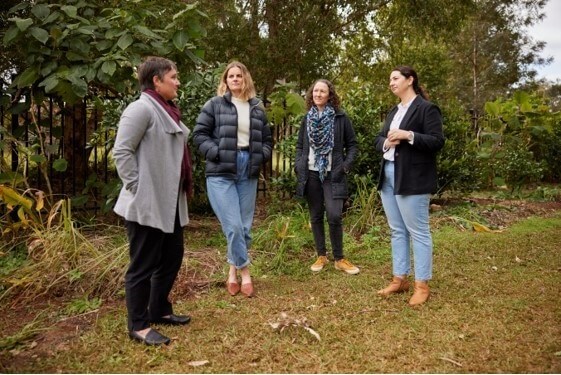 4 women standing outside in a circle