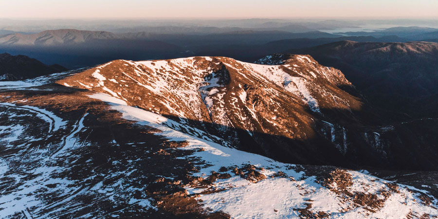 Landscape showing the sun lighting up a mountain at sunrise in the snowy mountains, NSW 