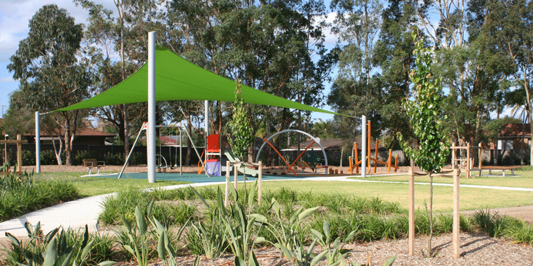 Shade sails, trees and gardens in an urban playground.