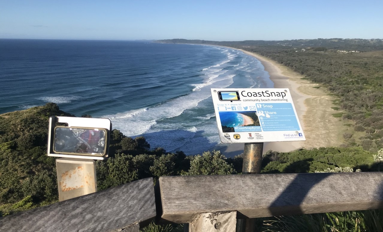 photograph of an iphone holder overlooking a beach with a sign in the foreground